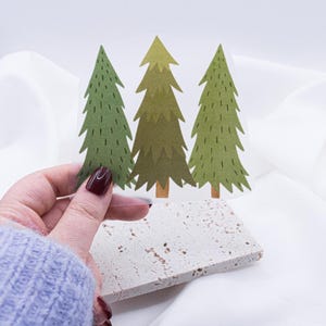 Könnte beinhalten: Drei grüne Tannenbäume mit braunen Stämmen auf einem transparenten Hintergrund. Die Bäume sind stilisiert und haben einen cartoonartigen Look.