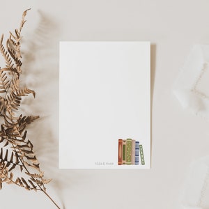 Peut inclure: Une carte blanche vide avec une pile de livres color&eacute;s en bas. Le texte "Read & Thrive" est imprim&eacute; sous les livres.