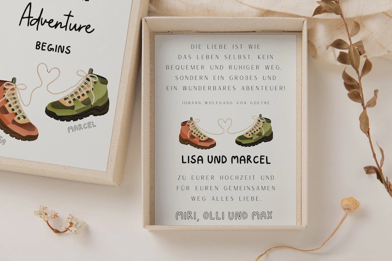May include: A white card with a quote about love being an adventure, illustrated with two hiking boots tied together with a heart-shaped string. The card reads "Lisa und Marcel" and "Zu eurer Hochzeit und fur euren gemeinsamen Weg alles Liebe. Miri, Olli und Max."
