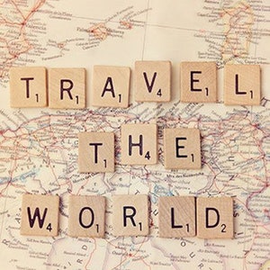 May include: A vintage world map with the phrase "TRAVEL THE WORLD" spelled out using letter tiles. The tiles are arranged in two rows, with the first row spelling "TRAVEL" and the second row spelling "THE WORLD".