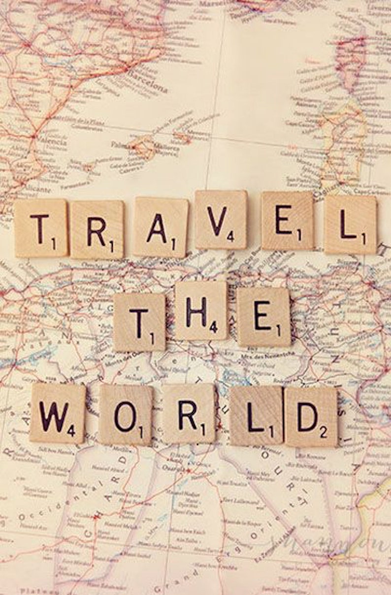May include: A vintage world map with the phrase "TRAVEL THE WORLD" spelled out using letter tiles. The tiles are arranged in two rows, with the first row spelling "TRAVEL" and the second row spelling "THE WORLD".