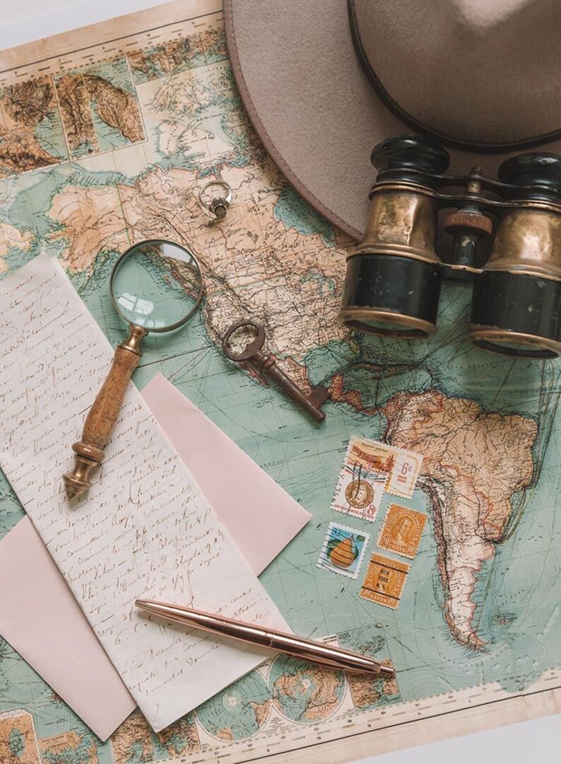 May include: A vintage world map with a magnifying glass, a pair of binoculars, a key, a pen, and a pink envelope. The map is faded and has a blue and green color scheme. There are several stamps on the map.