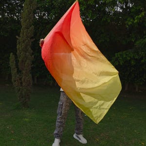May include: A large, rectangular worship flag featuring a vibrant gradient color scheme that transitions from deep red at the top corner to bright orange and finally to a light yellow hue at the bottom edge, made of lightweight fabric.