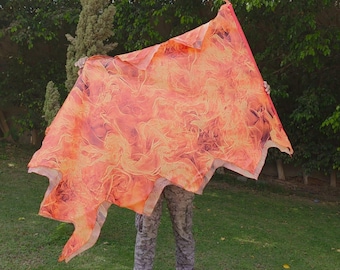 Op de afbeelding: Een groot, rechthoekig stuk stof met een levendige, abstracte print van wervelende oranje, rode en gele vlammen. Het materiaal is lichtgewicht en halfdoorschijnend, met een vurig patroon dat het gehele oppervlak bedekt.