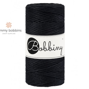 May include: A spool of black cotton cord, labelled "Bobbiny", for crafting projects.