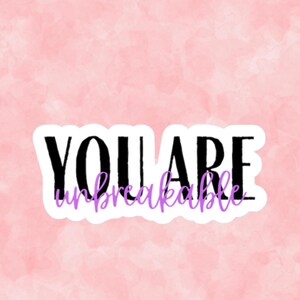 May include: A sticker with the words "YOU ARE unbreakable" in black and purple lettering. The sticker is on a pink watercolor background.