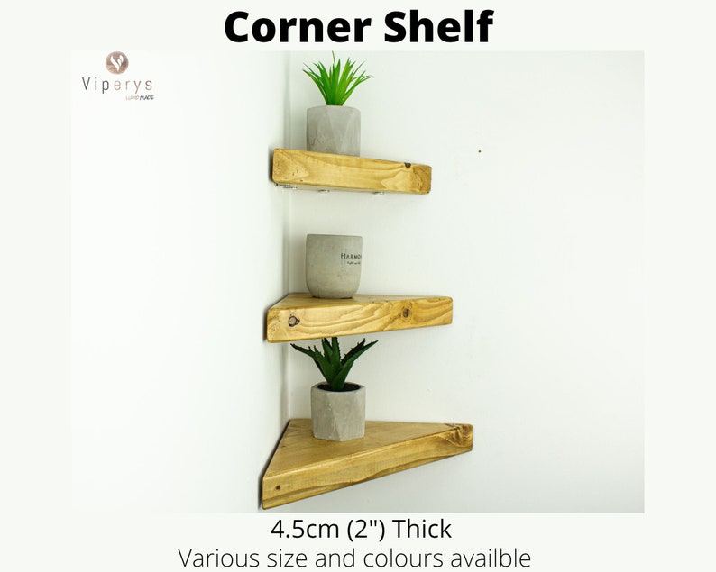 Peut inclure: Trois &eacute;tag&egrave;res d'angle en bois avec une finition en bois naturel. Les &eacute;tag&egrave;res ont une &eacute;paisseur de 4,5 cm (2 pouces) et sont pr&eacute;sent&eacute;es avec des plantes en pot. Le texte "Corner Shelf" est en haut de l'image. Le texte "Various size and colours available" est en bas de l'image.