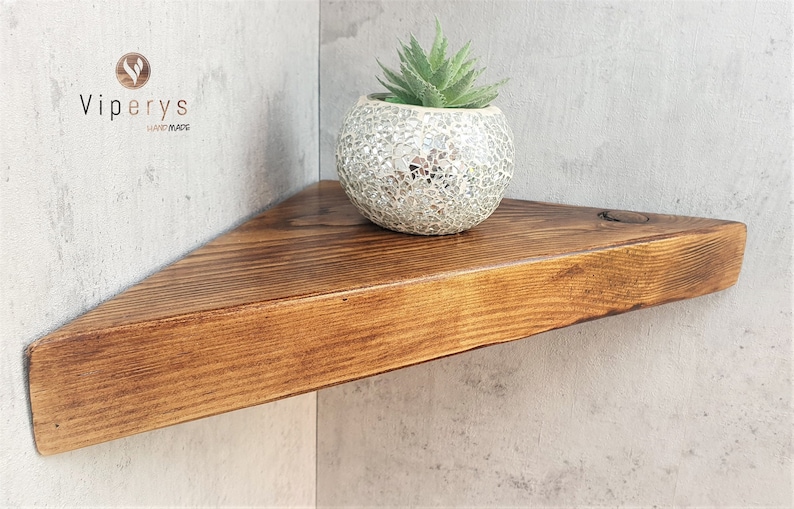 Peut inclure: Une &eacute;tag&egrave;re triangulaire en bois avec une finition en bois naturel. L'&eacute;tag&egrave;re est mont&eacute;e sur un mur et a une petite plante succulente en pot sur le dessus.