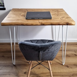 Könnte beinhalten: Ein Holztisch mit einer Live-Edge-Oberfläche und Haarnadelbeinen. Ein Laptop steht auf dem Tisch. Ein grauer Samtstuhl mit Holzbeinen steht vor dem Tisch.
