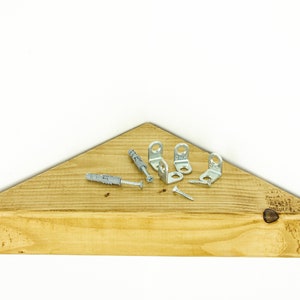 May include: A triangular wooden shelf with a light brown stain. The shelf is accompanied by four metal corner brackets and two screws.
