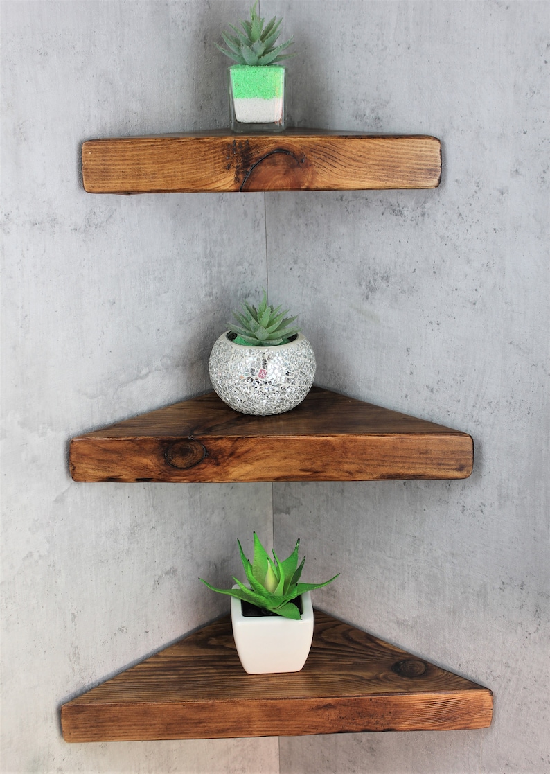 Peut inclure: Trois &eacute;tag&egrave;res d'angle en bois avec une finition brune rustique. Chaque &eacute;tag&egrave;re est d&eacute;cor&eacute;e d'une petite plante succulente en pot. L'&eacute;tag&egrave;re du haut a une succulente verte, l'&eacute;tag&egrave;re du milieu a une succulente argent&eacute;e et l'&eacute;tag&egrave;re du bas a une succulente blanche.