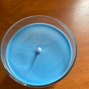 K&ouml;nnte beinhalten: Eine blaue Kerze in einem durchsichtigen Glasgef&auml;&szlig; mit einem wei&szlig;en Docht.
