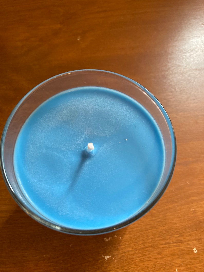 K&ouml;nnte beinhalten: Eine blaue Kerze in einem durchsichtigen Glasgef&auml;&szlig; mit einem wei&szlig;en Docht.