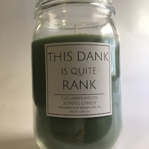 May include: A green scented candle in a glass jar with the text "This dank is quite rank" and "Cucumber Melon Scented Candle Handmade in Milwaukee, WI Crude Candles".