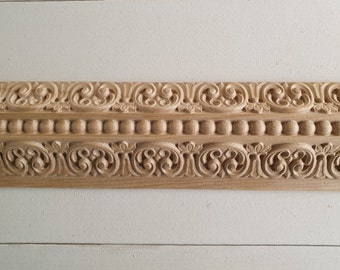 May include: A close-up of a wooden decorative molding with intricate carvings. The molding features a repeating pattern of swirls and beads, creating a classic and elegant design.