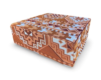 May include: A rectangular ottoman with a geometric pattern in shades of orange, brown, white, and light blue. The design features repeating shapes and lines, creating a textured appearance. The ottoman is a low, square shape.