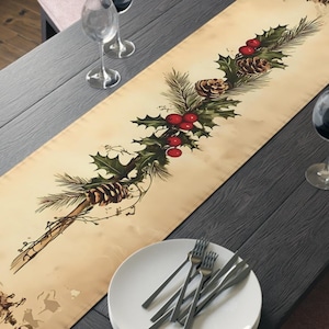 Puede incluir: Un camino de mesa beige con un diseño festivo con acebo, piñas y bayas rojas. El camino de mesa está colocado sobre una mesa de madera oscura preparada para una comida, con platos, cubiertos y copas de vino. Un cuenco de manzanas y peras está en la parte superior.