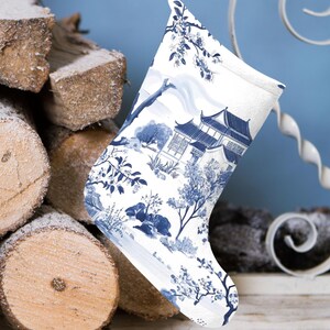 Könnte beinhalten: Ein weißer Weihnachtssocken mit einem blauen und weißen Blumenmuster, das eine traditionelle chinesische Pagode und Bäume zeigt. Der Socken hängt an einem Kaminsims.