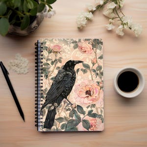 May include: A black crow with a floral pattern background. The crow is perched on a branch with pink roses and green leaves. The background is a light beige with a subtle floral pattern.