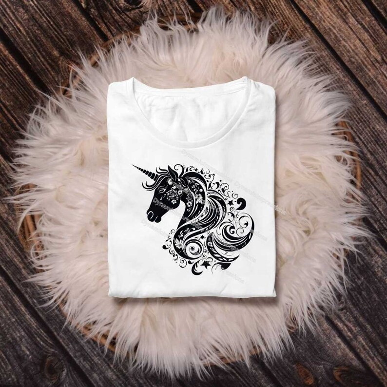 以下が含まれることがあります： 白いTシャツに、黒と白のユニコーンの頭と花のデザインのグラフィックがプリントされています。