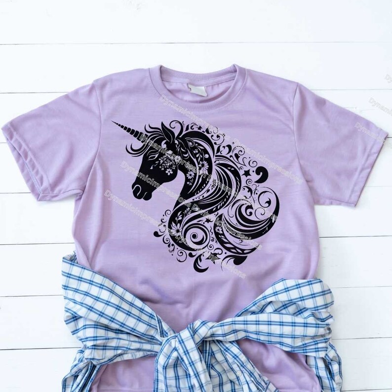 以下が含まれることがあります： ラベンダー色のTシャツに、黒いシルエットで描かれた花柄のユニコーンの頭部がデザインされています。