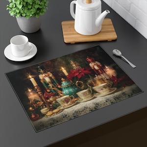 Op de afbeelding: Een decoratieve placemat met een feestelijke kerstscène. De afbeelding toont theekopjes, een theepot, kaarsen, notenkrakers en poinsettia's. De placemat ligt op een zwart oppervlak en creëert een warme en uitnodigende vakantiesfeer.