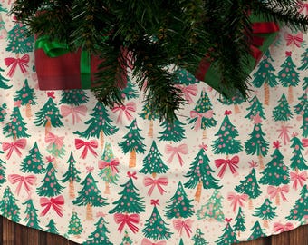 Könnte beinhalten: Ein weißer Christbaumrock mit einem grünen und rosa Muster aus Weihnachtsbäumen und Schleifen. Der Rock ist mit kleinen weißen Punkten verziert.