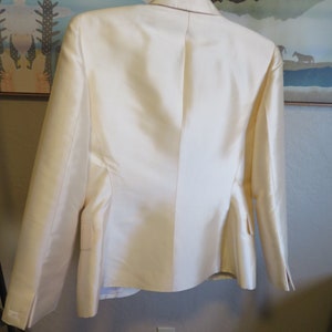 Op de afbeelding: Een wit blazer met een satijnen afwerking. De blazer heeft een klassieke snit met lange mouwen en een enkele knoopsluiting.
