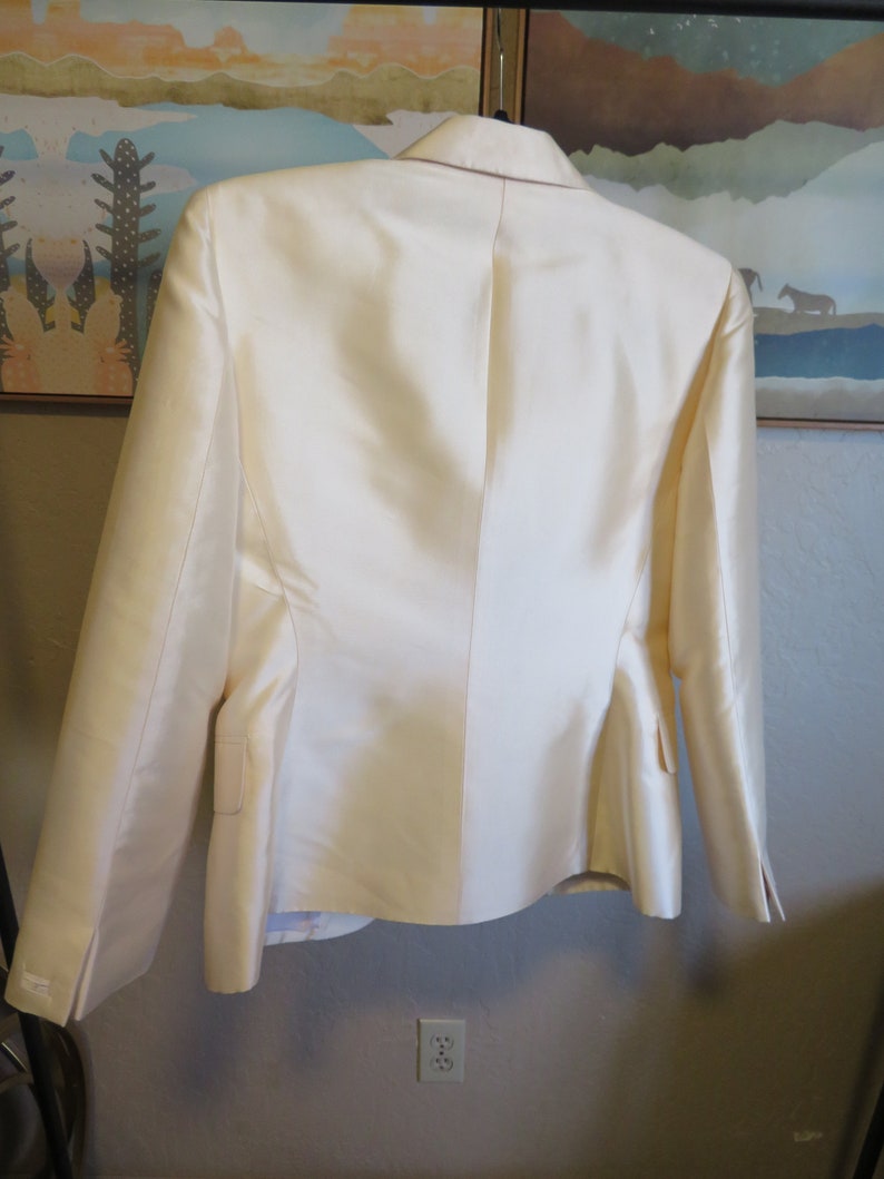 Op de afbeelding: Een wit blazer met een satijnen afwerking. De blazer heeft een klassieke snit met lange mouwen en een enkele knoopsluiting.