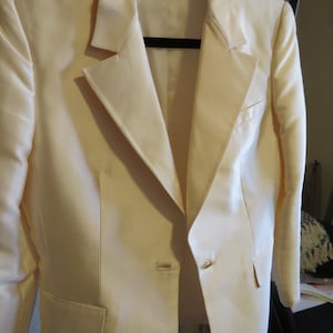 Op de afbeelding: Een wit blazer met een enkele knoopsluiting en een zak aan de linkerkant. De blazer heeft een satijnachtige afwerking en een label met de tekst "Made in Italy".