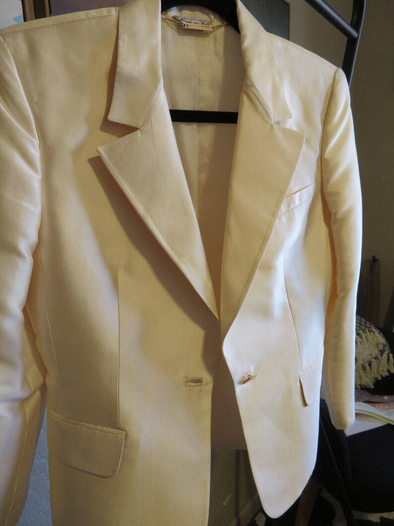Op de afbeelding: Een wit blazer met een enkele knoopsluiting en een zak aan de linkerkant. De blazer heeft een satijnachtige afwerking en een label met de tekst "Made in Italy".