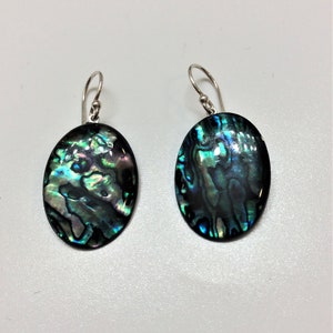 May include: A pair of silver dangle earrings with oval-shaped abalone shell pendants. The shells have a blue, green, and iridescent color pattern.