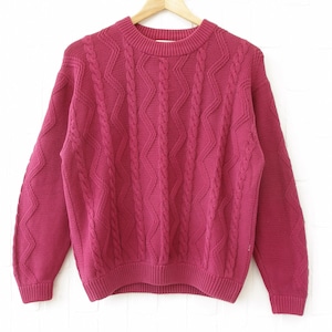 May include: A deep pink cable knit jumper with a crew neck.
