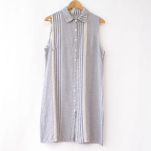 May include: A sleeveless button-up shirt dress with a striped pattern in blue and white.