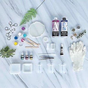 K&ouml;nnte beinhalten: Ein Harz-Gie&szlig;set mit zwei Flaschen Harz, eine mit der Aufschrift "Casting Resin" und die andere mit der Aufschrift "Resin Hardener". Das Set enth&auml;lt au&szlig;erdem eine Vielzahl von Werkzeugen, wie z. B. Mischst&auml;bchen, Messbecher und Handschuhe.