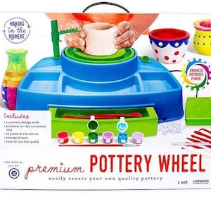 May include: A blue and green pottery wheel toy set with a foot pedal, clay, paint, and tools. The box says "premium pottery wheel" and "easily create your own quality pottery".