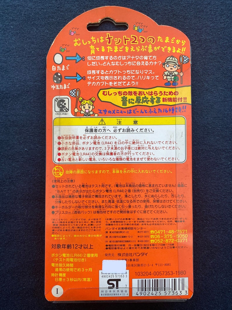May include: A red and white cardboard box with a picture of a cartoon character holding a net. The box is for a toy called "Oicch! Kett 2" and features the text "What kind of egg will you choose?" and "Grow your own egg!" The box also includes a warning label and instructions for use.