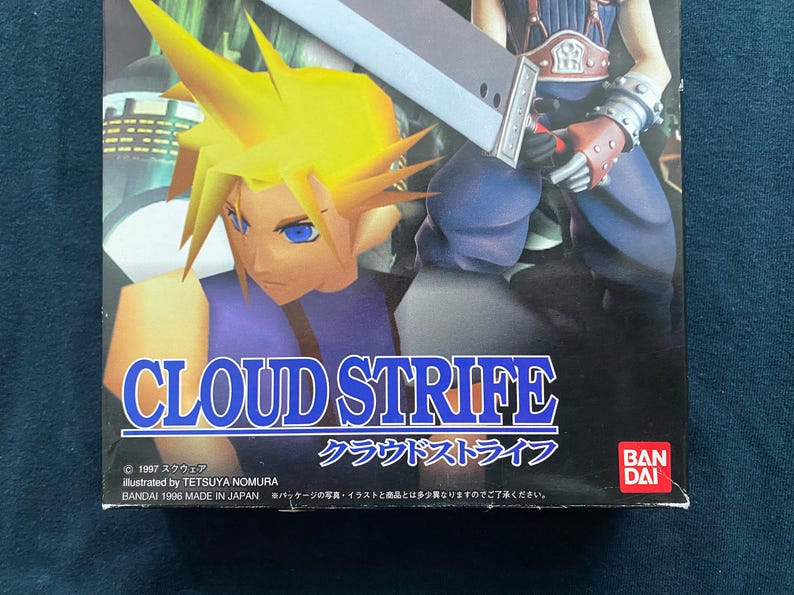 May include: Box art for the video game Cloud Strife, featuring a character with spiky yellow hair and a large sword. The title "CLOUD STRIFE" is prominently displayed in white and blue. The Bandai logo is visible.