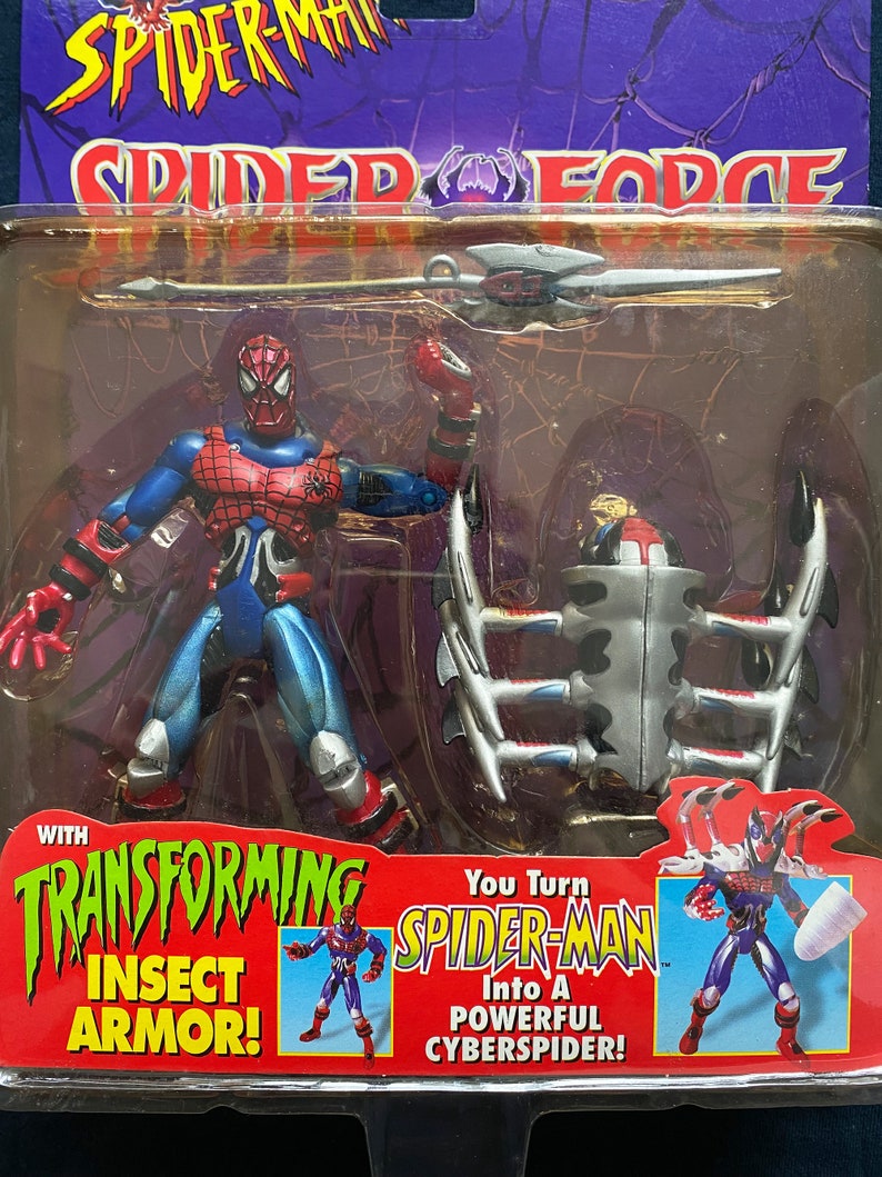 May include: Spider-Man action figure with transforming insect armor. The figure is red and blue with a black spider symbol on the chest. The figure comes with a silver spear and a transforming insect armor that can be attached to the figure. The packaging features the text "You Turn Spider-Man Into A Powerful CyberSpider!"
