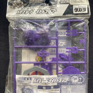 May include: A sealed plastic package containing a purple Beyblade Knight Dranzer model kit. The set includes purple plastic components on a frame, a metal ring, and an instruction sheet with Japanese text and graphics featuring the Beyblade logo.