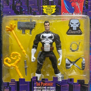 May include: A plastic action figure of The Punisher from the animated series Spider-Man. The Punisher is wearing his signature black and white costume with a skull emblem on his chest. The figure comes with a variety of accessories, including a gun, a whip, and a grappling hook. The packaging features a background of city buildings and the text "The Punisher" and "Immobilizing Arsenal!"