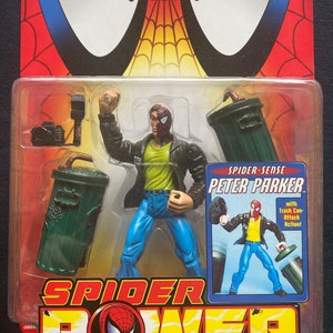 May include: A Spider-Man action figure in a red and black suit with a yellow shirt and blue jeans. The figure is holding a trash can in one hand and a web shooter in the other. The figure is packaged in a plastic blister pack with a red, black, and yellow background. The packaging includes the text "Spider-Sense Peter Parker" and "with Trash Can Attack Action!"