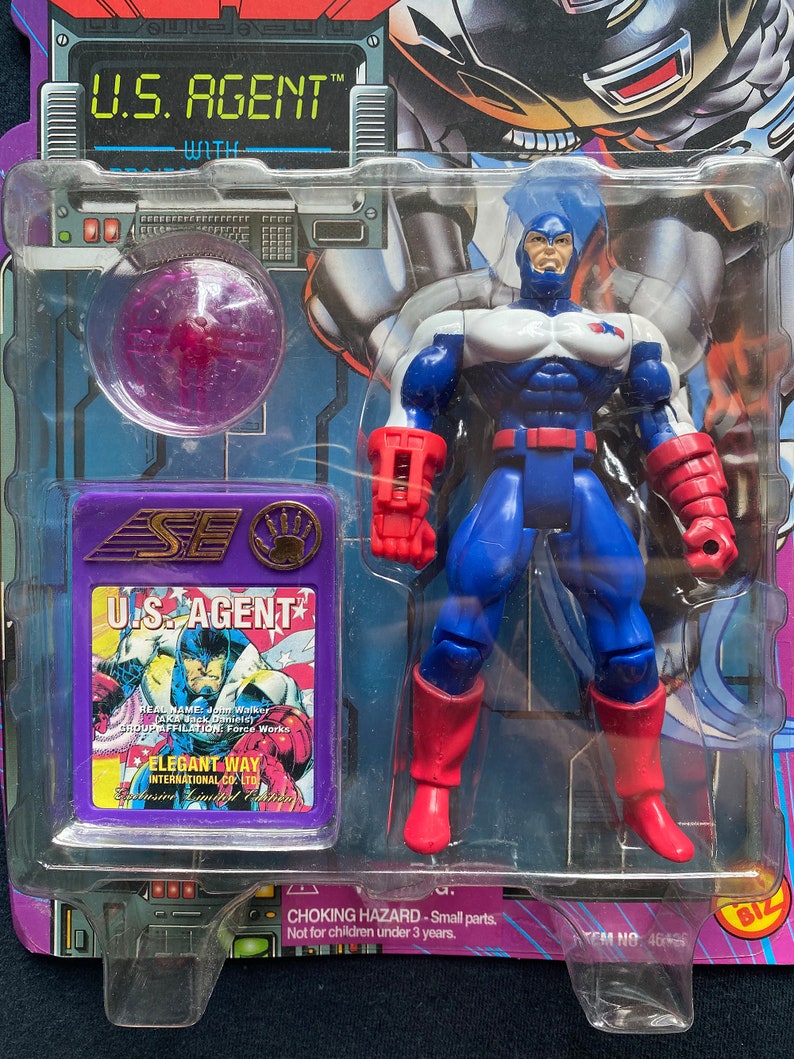 K&ouml;nnte beinhalten: Eine Plastik-Actionfigur von U.S. Agent, einem Superhelden aus Marvel Comics. Die Figur tr&auml;gt ein blaues, wei&szlig;es und rotes Kost&uuml;m mit einem roten Helm. Die Figur h&auml;lt eine rot-schwarze Waffe in ihrer rechten Hand. Die Figur ist in einer Plastik-Blisterverpackung mit violettem Hintergrund verpackt. Die Verpackung enth&auml;lt ein kleines Comic-Heft mit U.S. Agent.