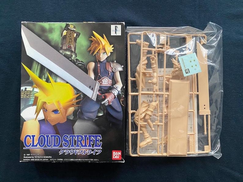May include: A boxed Cloud Strife model kit with a character illustration on the front. The box features a character with spiky yellow hair holding a large sword. Next to it is a plastic model kit with unassembled parts.
