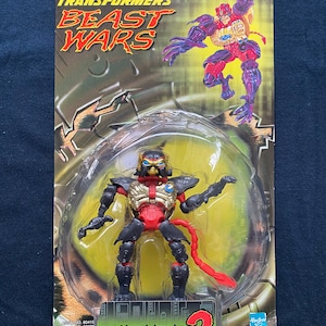 以下が含まれることがあります： トランスフォーマービーストウォーズトランスメタルズ2の赤と黒のオプティマス・マイナーのアクションフィギュア。フィギュアは黄色の背景のプラスチック製のブリスターパックに入っています。フィギュアは金の胸板と赤い尻尾を持っています。