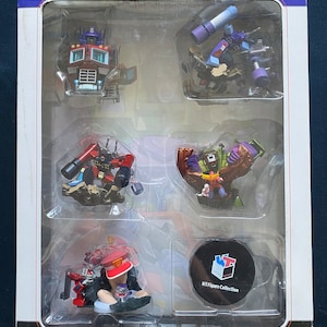 Puede incluir: Un conjunto completo de seis figuras de Transformers en una caja de plástico transparente. Las figuras son de la serie Transformers: Robots in Disguise. La caja está etiquetada con "KT Figure Collection" y "Transformers: Robots in Disguise".