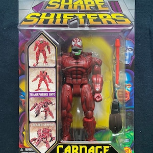 May include: Carnage action figure from the Marvel Shape Shifters line. The figure is red and transforms into a three-headed serpent. The packaging features a photo of the figure in both forms.