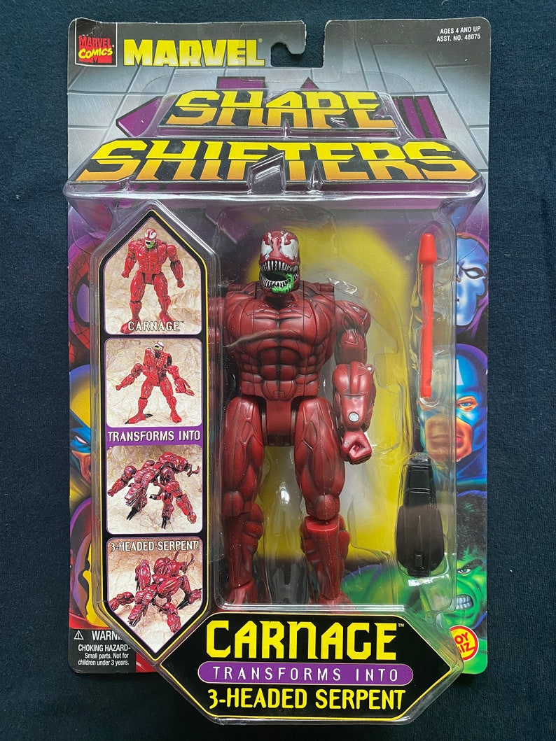 May include: Carnage action figure from the Marvel Shape Shifters line. The figure is red and transforms into a three-headed serpent. The packaging features a photo of the figure in both forms.