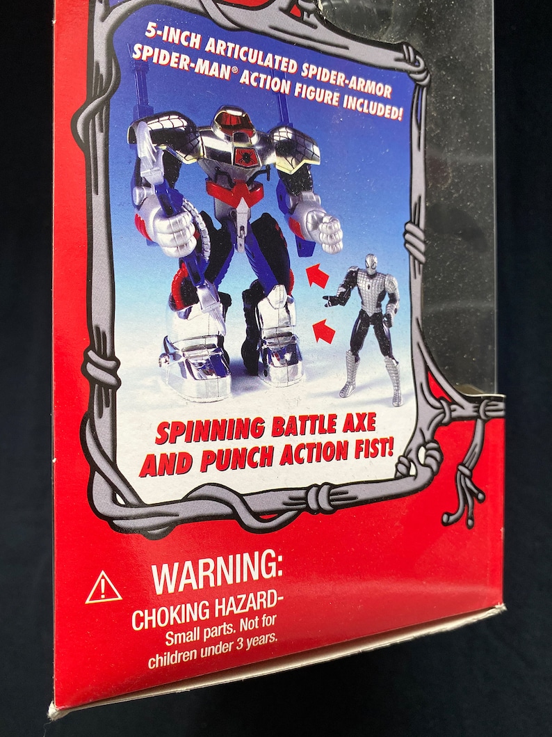 Pode incluir: Uma caixa de cart&atilde;o vermelha e branca com um r&oacute;tulo de advert&ecirc;ncia. A caixa apresenta uma figura de a&ccedil;&atilde;o articulada do Homem-Aranha de 12,7 cm em um traje de Spider-Armor prateado e azul. A figura tem um machado de batalha girat&oacute;rio e um punho de a&ccedil;&atilde;o. O texto na caixa diz "Figura de a&ccedil;&atilde;o articulada do Homem-Aranha de 12,7 cm em Spider-Armor inclu&iacute;da!" e "Machado de batalha girat&oacute;rio e punho de a&ccedil;&atilde;o!"