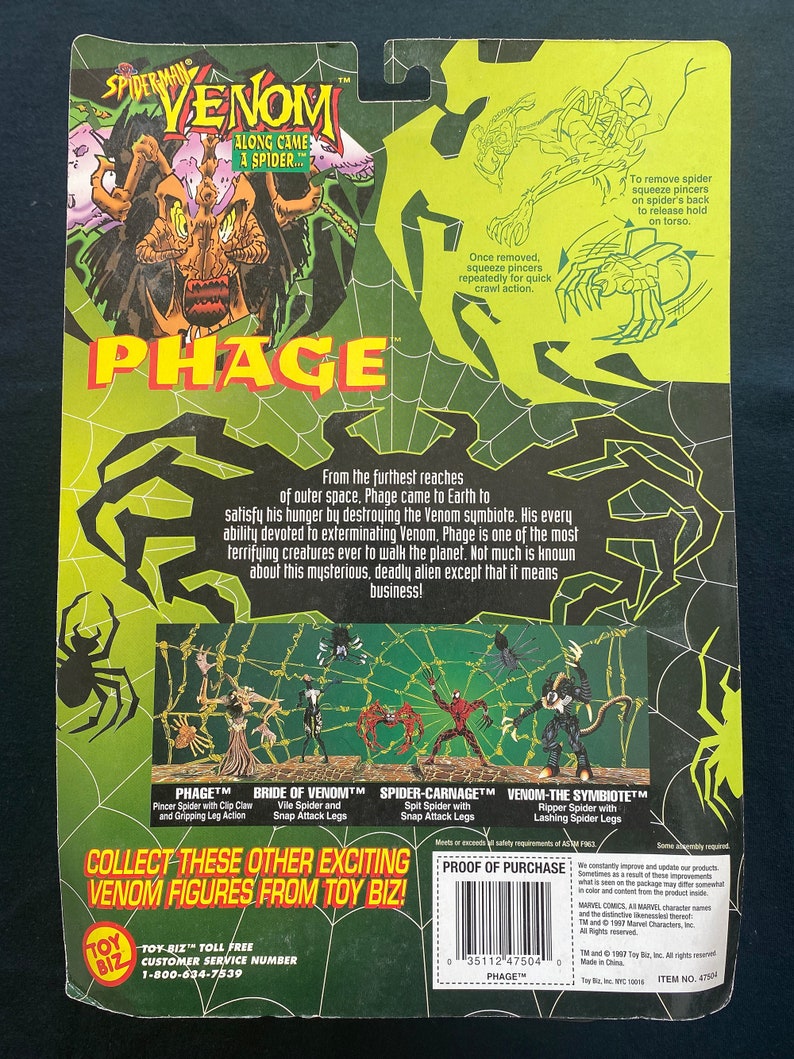 May include: A green, black, and red action figure packaging for a Spider-Man Venom character called Phage. The packaging features a cartoon image of the character and a description of the character's origin and abilities. The packaging also includes a list of other Venom figures available from Toy Biz.